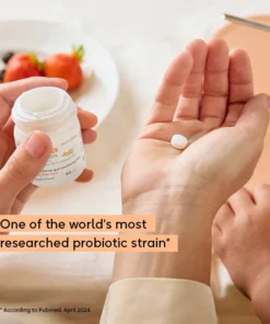 Close-up of a person's hand holding a single white pill with the other hand holding an open white pill bottle, with a blurred background featuring a plate with strawberries and dark berries, and text overlay stating 